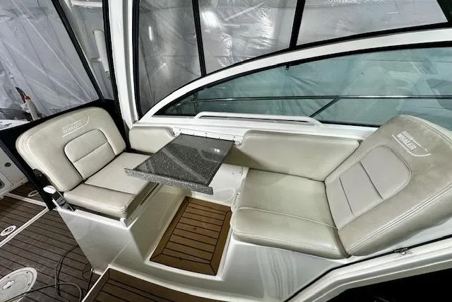  Yacht Photos Pics 2016 Boston Whaler 285 Conquest interior seating with table, featuring cushioned seats and wood flooring.