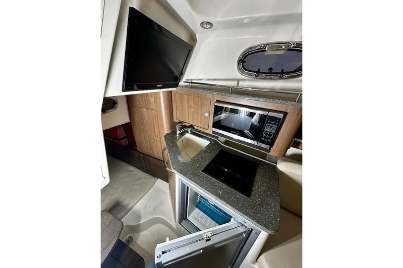  Yacht Photos Pics 2016 Boston Whaler 285 Conquest cabin with kitchenette, featuring a TV, microwave, and sink.