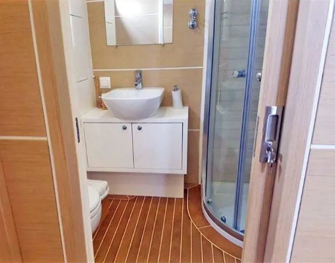  Yacht Photos Pics Modern yacht bathroom with wooden flooring, white sink, and glass shower in a 2017 Custom GULET.