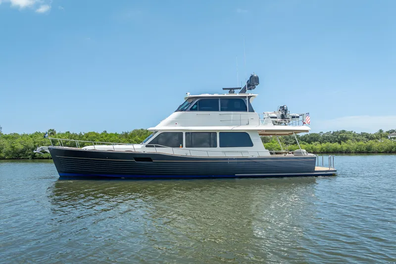 Escape Yacht Photos Pics 2022 Grand Banks GB60 yacht on calm water under clear blue sky.