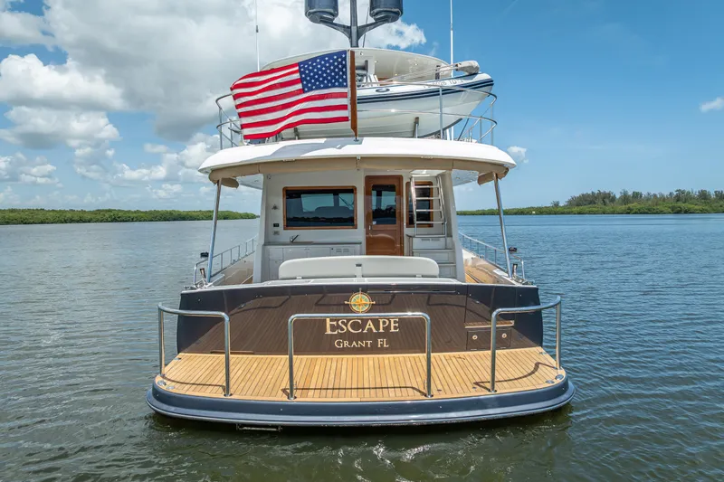 Escape Yacht Photos Pics 2022 Grand Banks GB60 yacht on water, American flag, clear sky.