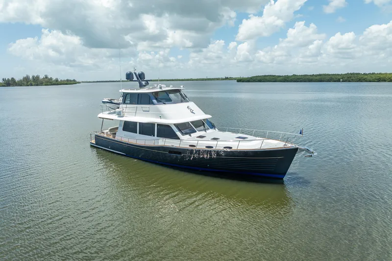 Escape Yacht Photos Pics 2022 Grand Banks GB60 yacht on calm water under a partly cloudy sky.