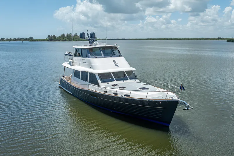 Escape Yacht Photos Pics 2022 Grand Banks GB60 yacht cruising on calm waters under a partly cloudy sky.