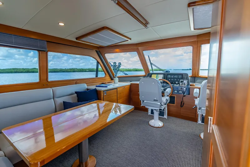 Escape Yacht Photos Pics Luxurious interior of 2022 Grand Banks GB60 Skylounge yacht with panoramic windows and elegant seating.