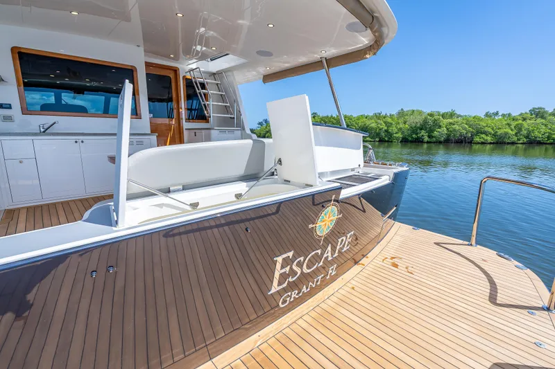 Escape Yacht Photos Pics 2022 Grand Banks GB60 Skylounge yacht, elegant deck view, docked by lush greenery.