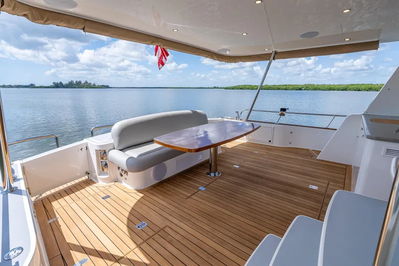 Escape Yacht Photos Pics Luxurious 2022 Grand Banks GB60 Skylounge yacht deck with elegant seating and scenic water view.