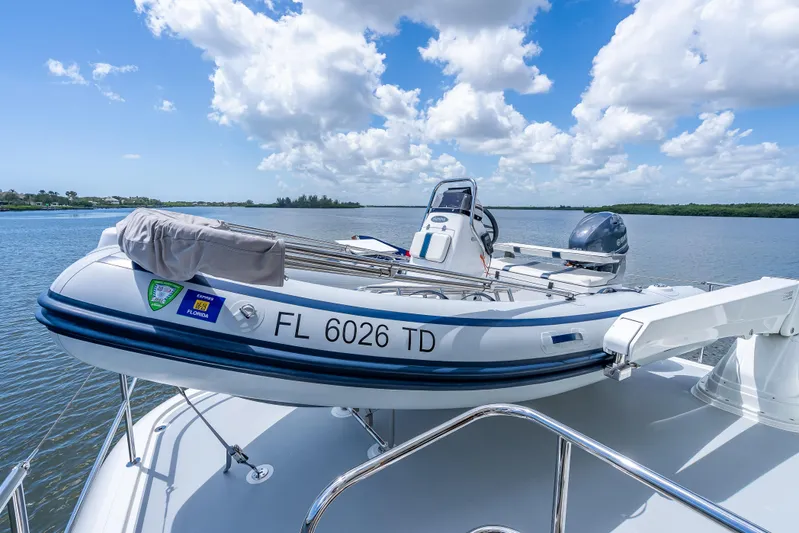 Escape Yacht Photos Pics 2022 Grand Banks GB60 Skylounge with tender boat on deck, under a bright blue sky.