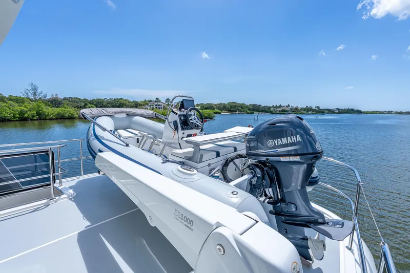 Escape Yacht Photos Pics 2022 Grand Banks GB60 Skylounge yacht with Yamaha motorboat on deck, scenic water view.