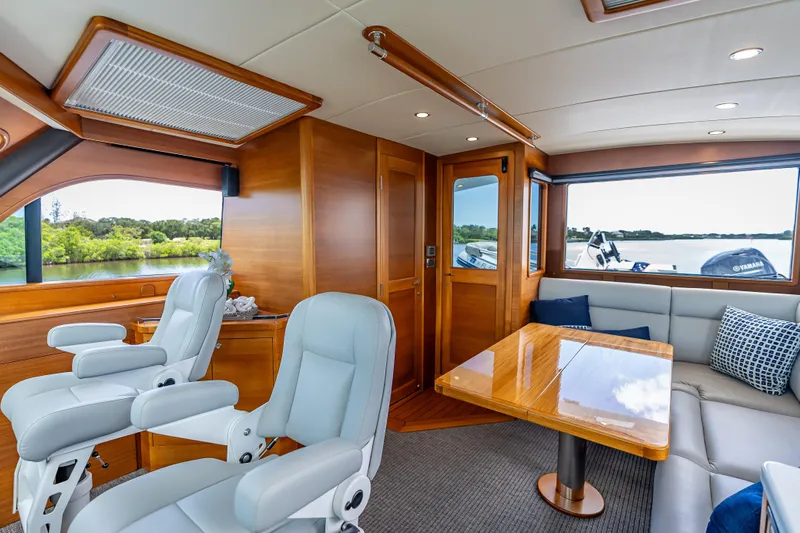 Escape Yacht Photos Pics Luxurious 2022 Grand Banks GB60 Skylounge interior with plush seating and scenic window views.