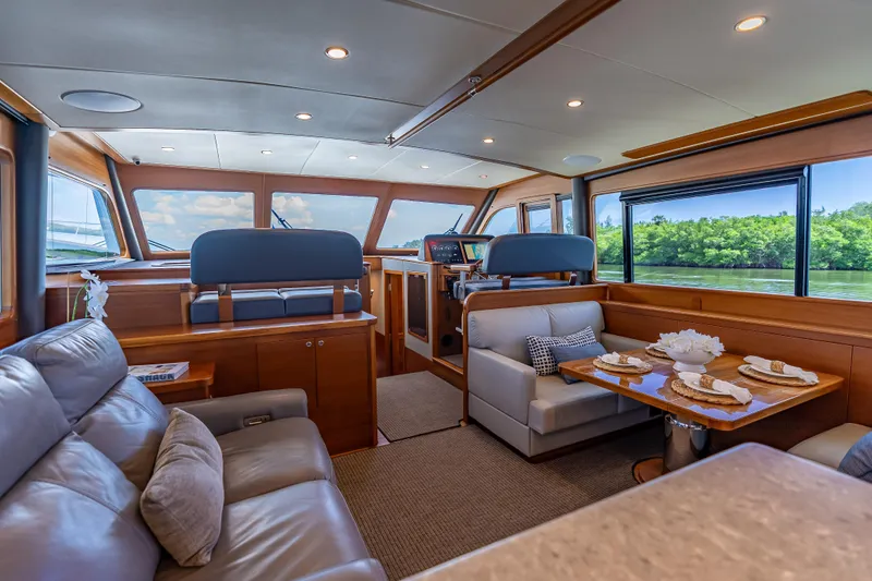 Escape Yacht Photos Pics Luxurious interior of 2022 Grand Banks GB60 Skylounge yacht with elegant seating and dining area.