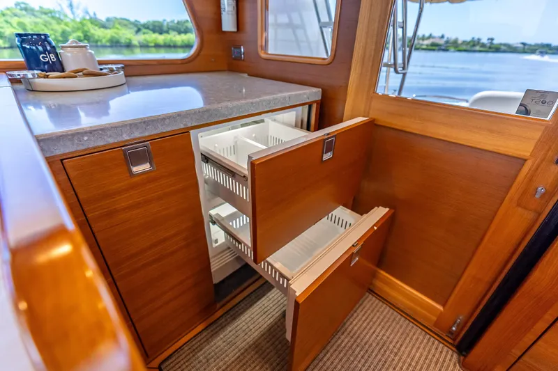 Escape Yacht Photos Pics 2022 Grand Banks GB60 Skylounge interior with open wooden cabinets and scenic window view.