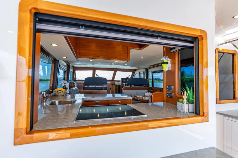 Escape Yacht Photos Pics Luxurious interior of 2022 Grand Banks GB60 Skylounge yacht with modern kitchen and seating area.