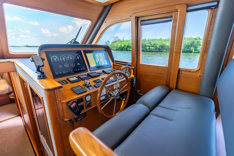 Escape Yacht Photos Pics 2022 Grand Banks GB60 Skylounge helm with navigation screens and wooden interior.