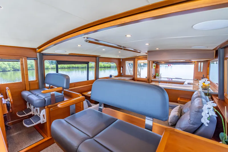 Escape Yacht Photos Pics Luxurious 2022 Grand Banks GB60 Skylounge interior with elegant wood finish and comfortable seating.