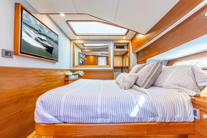 Escape Yacht Photos Pics Luxurious bedroom interior of 2022 Grand Banks GB60 Skylounge yacht, featuring elegant wood finishes.