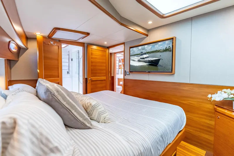 Escape Yacht Photos Pics Luxurious 2022 Grand Banks GB60 Skylounge bedroom with elegant wood finishes and modern amenities.