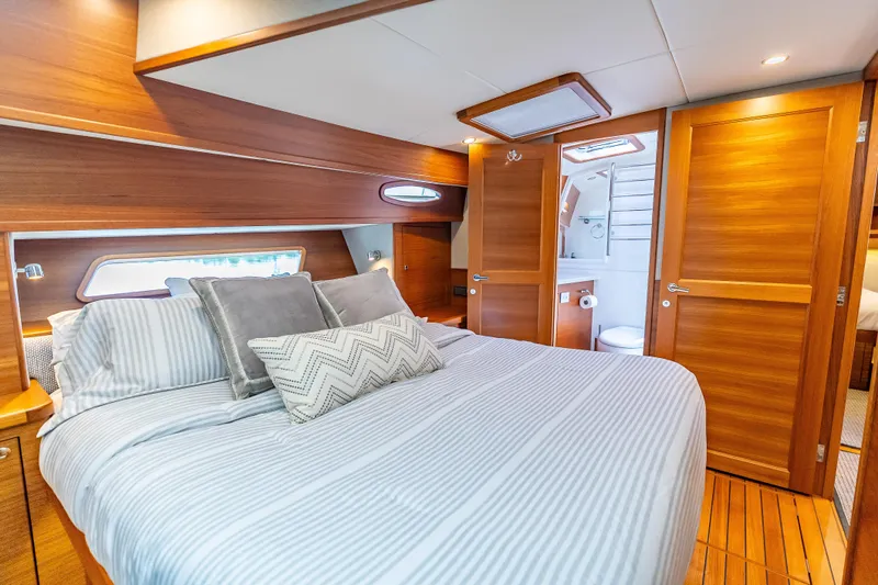 Escape Yacht Photos Pics Luxurious bedroom interior of 2022 Grand Banks GB60 Skylounge yacht with ensuite bathroom.