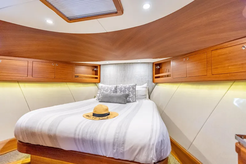 Escape Yacht Photos Pics Luxurious cabin interior of 2022 Grand Banks GB60 Skylounge yacht with cozy bed and wooden accents.