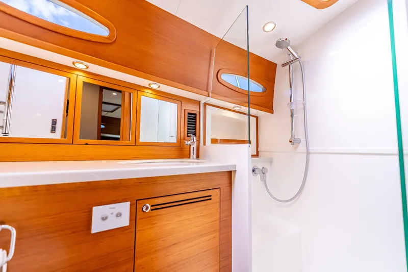 Escape Yacht Photos Pics Luxurious bathroom in 2022 Grand Banks GB60 Skylounge yacht with wood accents and modern fixtures.