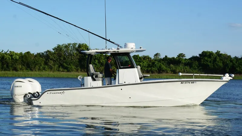  Yacht Photos Pics 2024 Freeman 28 boat on calm water with dual engines, lush greenery in background.