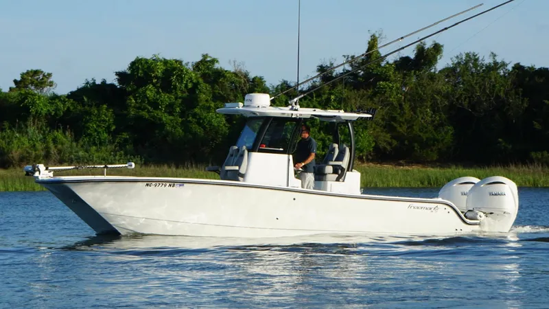  Yacht Photos Pics 2024 Freeman 28 boat cruising on a calm river with lush greenery in the background.