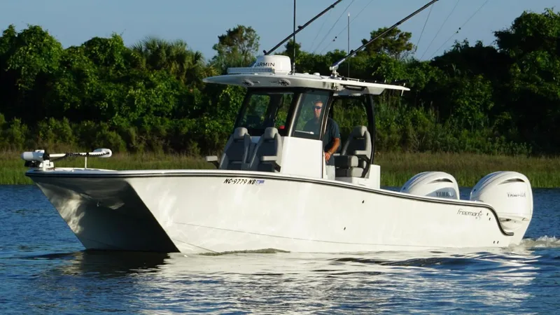  Yacht Photos Pics 2024 Freeman 28 boat cruising on a calm lake with lush greenery in the background.