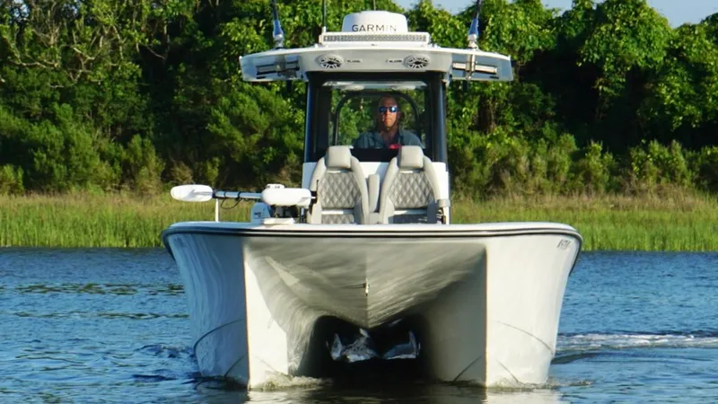  Yacht Photos Pics 2024 Freeman 28 boat cruising on a calm river with lush greenery in the background.