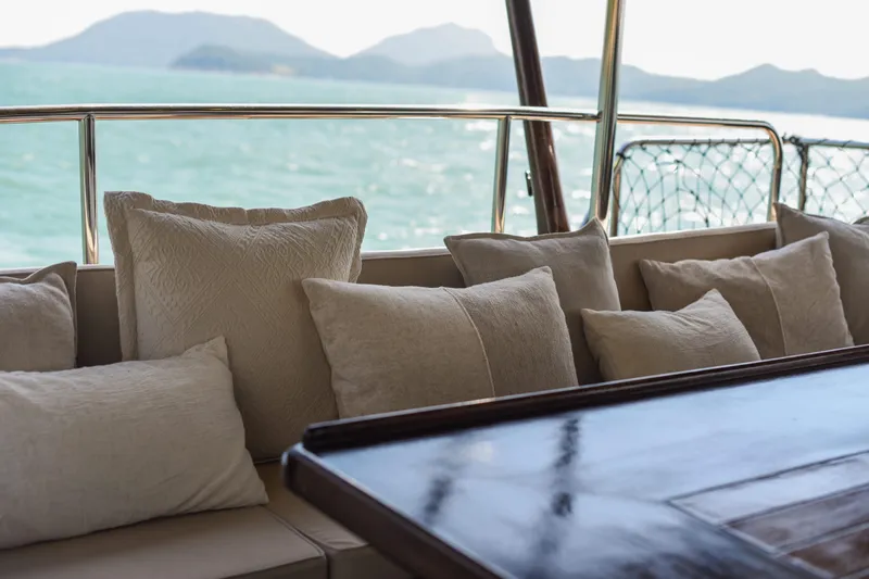 Gaiole Yacht Photos Pics Luxurious boat seating with cushions, overlooking serene ocean and distant mountains. Custom Junk, 1994.