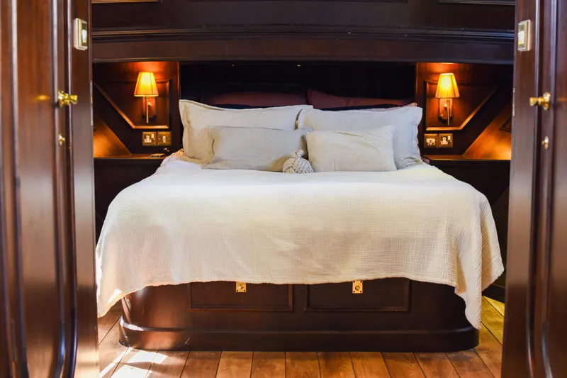 Gaiole Yacht Photos Pics Luxurious wooden bedroom interior with cozy bed and warm lighting, Custom Junk model, 1994.