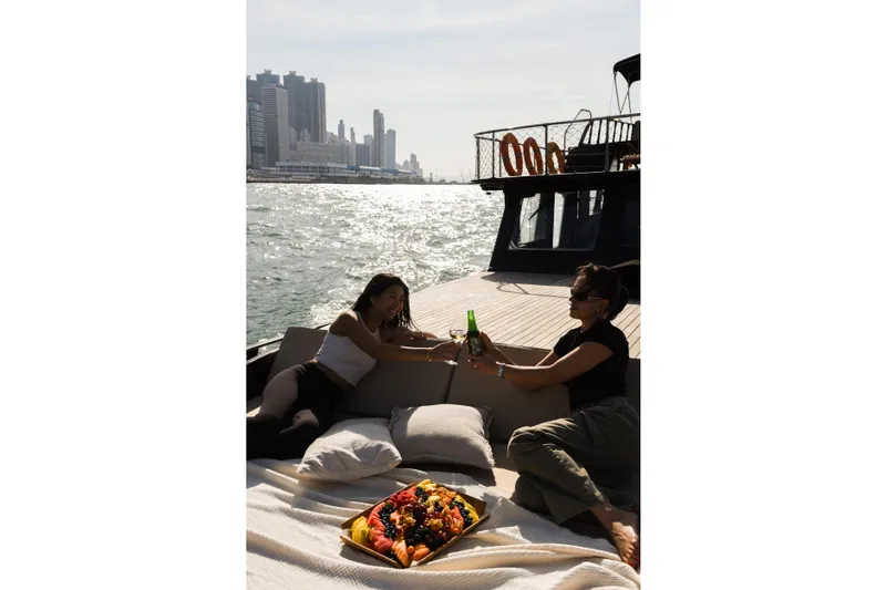 Gaiole Yacht Photos Pics Two people relaxing on a 1994 Custom Junk boat with city skyline backdrop.