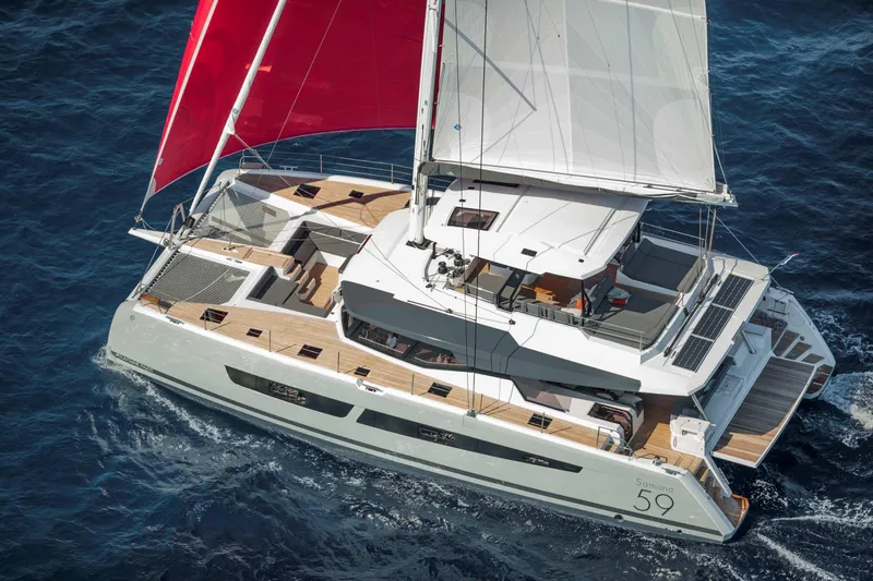  Yacht Photos Pics 2025 Fountaine Pajot Samana 59 catamaran sailing with red sails on open sea.