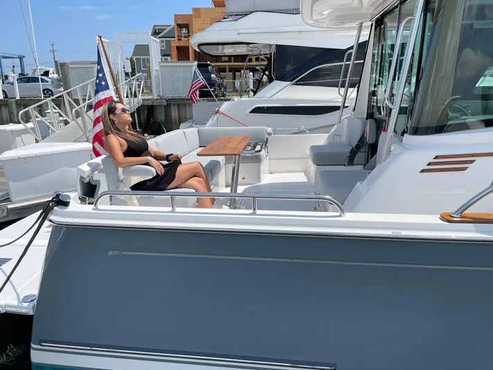  Yacht Photos Pics 2023 Sabre 43 Salon Express yacht with a person relaxing on deck, docked at a marina.