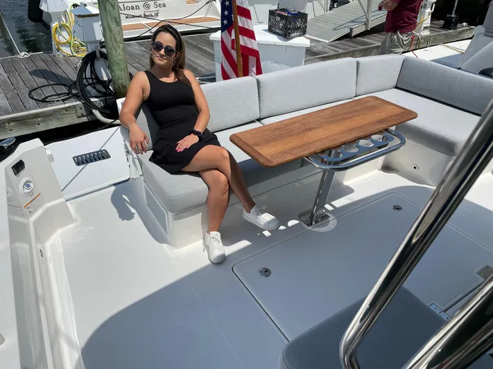  Yacht Photos Pics Woman relaxing on a 2023 Sabre 43 Salon Express yacht's deck with seating and table.