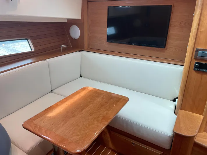  Yacht Photos Pics 2023 Sabre 43 Salon Express interior with white seating, wooden table, and mounted TV.