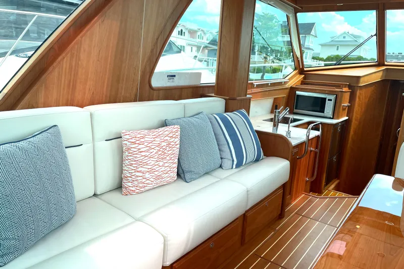  Yacht Photos Pics 2023 Sabre 43 Salon Express interior with white seating, striped cushions, and a compact kitchen area.