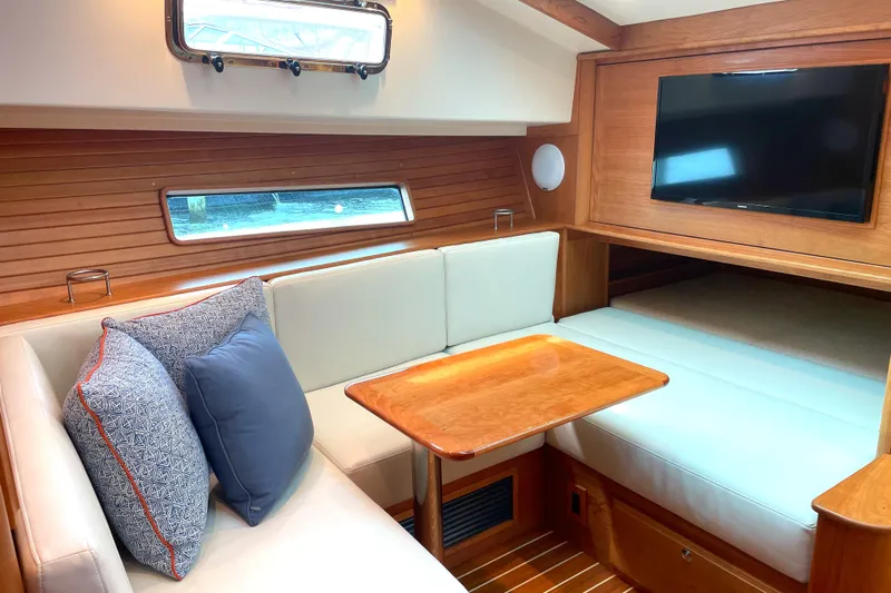  Yacht Photos Pics 2023 Sabre 43 Salon Express interior with cozy seating, wooden table, and mounted TV.