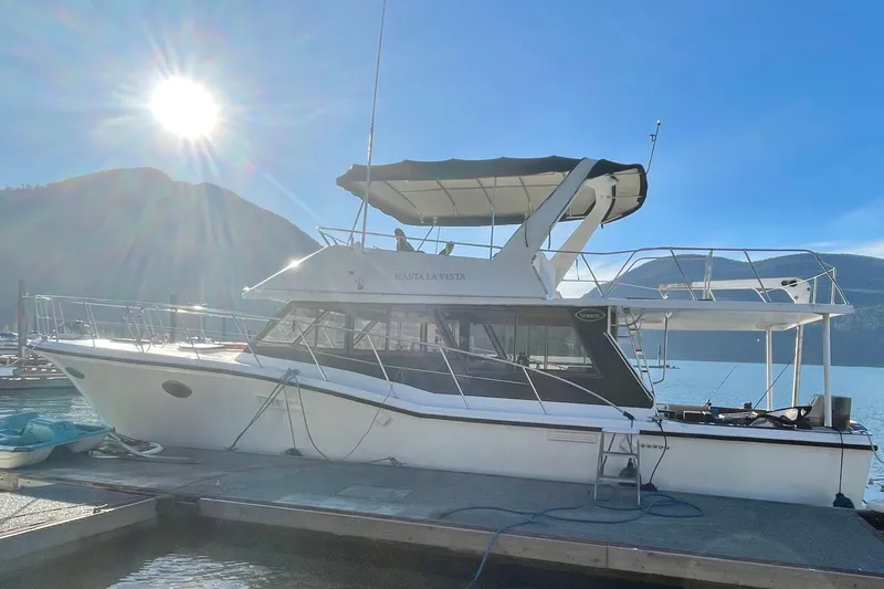 Hasta La Vista Yacht Photos Pics 1997 Symbol 48 Sportfish yacht docked under bright sun, scenic mountain backdrop.