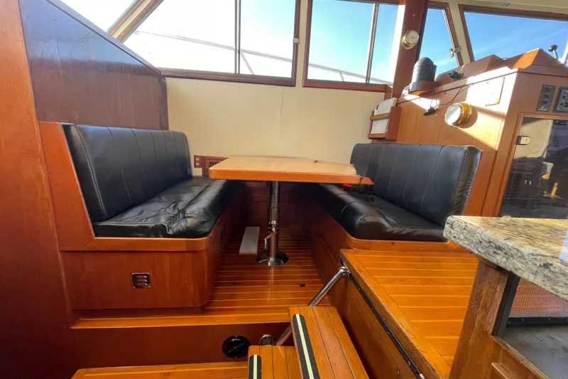 Hasta La Vista Yacht Photos Pics Interior of 1997 Symbol 48 Sportfish with wooden dining area and black leather seating.