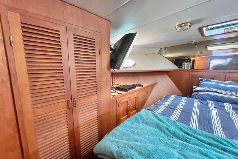 Hasta La Vista Yacht Photos Pics Cozy cabin interior of 1997 Symbol 48 Sportfish with striped bedding and wooden cabinetry.