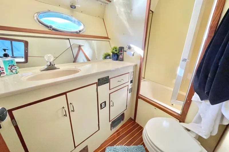 Hasta La Vista Yacht Photos Pics Bathroom interior of 1997 Symbol 48 Sportfish yacht, featuring sink, mirror, and shower.