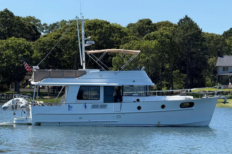  Yacht Photos Pics 2018 Beneteau Swift Trawler 44 on calm water, surrounded by lush greenery.