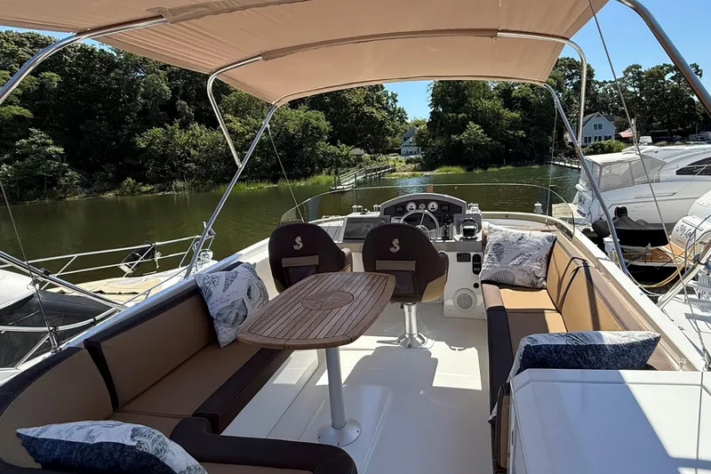  Yacht Photos Pics 2018 Beneteau Swift Trawler 44 with spacious outdoor seating and helm, docked by a serene river.