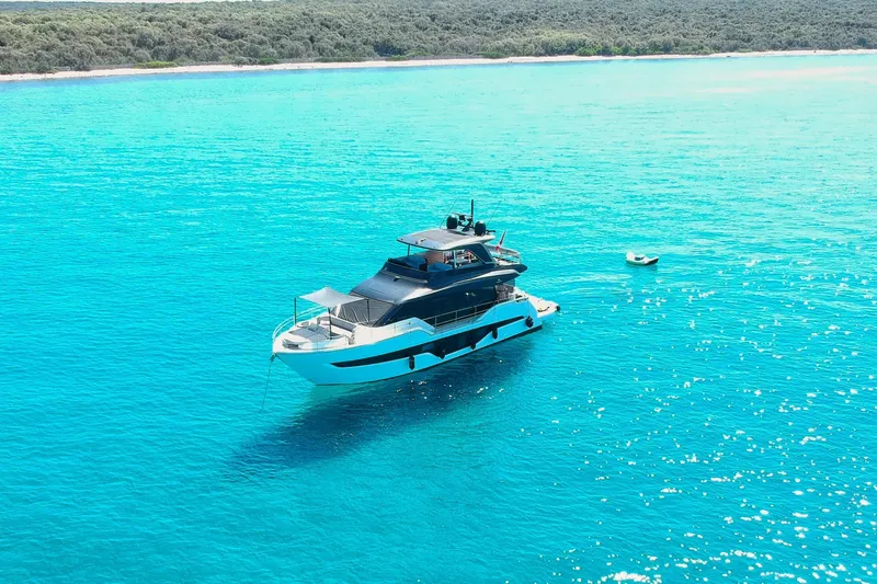 Amy Yacht Photos Pics 2023 Cranchi Sessantasette 67 yacht on turquoise water near lush coastline.