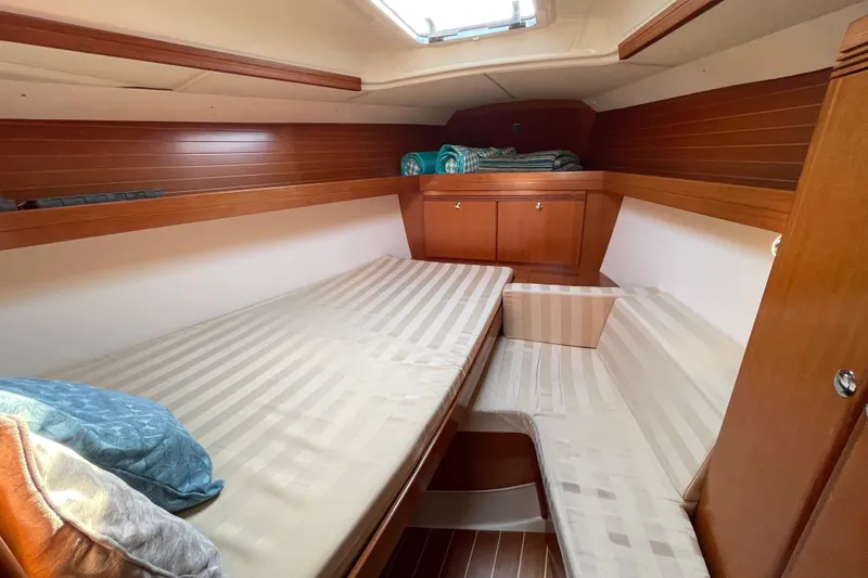 Jaacktak Yacht Photos Pics Cozy cabin interior of 2004 Dufour 40 Performance yacht with wooden finishes and striped bedding.