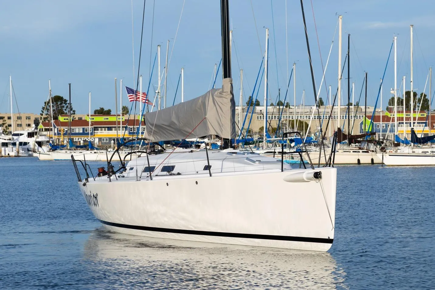 2008 J Boats J/122 sailboat docked in a marina with colorful buildings in the background.