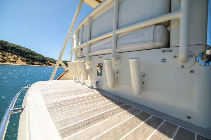 Barefoot Yacht Photos Pics 2014 Hinckley Talaria 48 Flybridge yacht deck with rod holders, near scenic shoreline.
