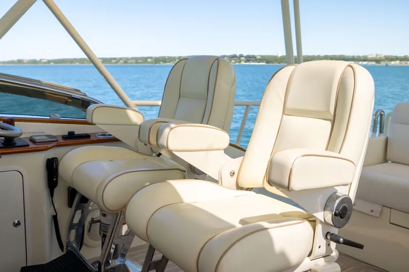 Barefoot Yacht Photos Pics Luxurious helm seats on 2014 Hinckley Talaria 48 Flybridge yacht, overlooking serene waters.