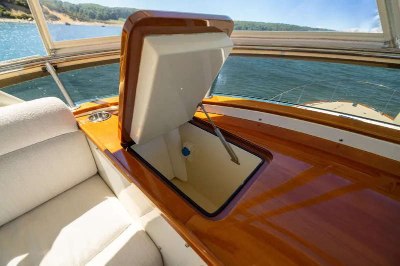 Barefoot Yacht Photos Pics Luxurious 2014 Hinckley Talaria 48 Flybridge interior with open storage compartment, overlooking serene waters.