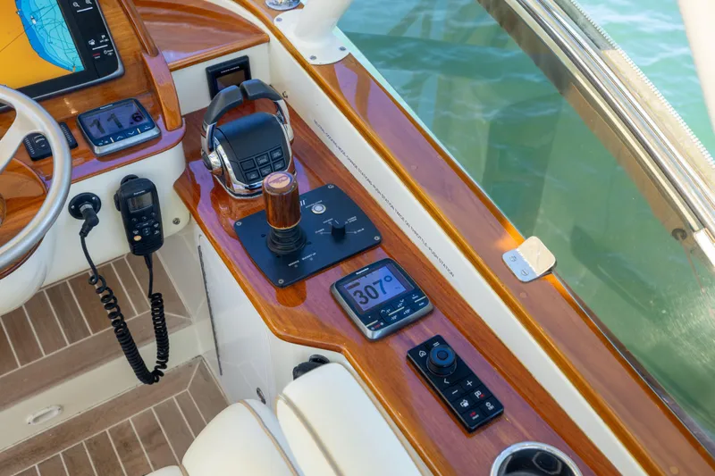 Barefoot Yacht Photos Pics Helm controls of 2014 Hinckley Talaria 48 Flybridge with navigation equipment and wooden accents.