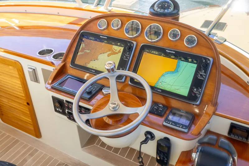 Barefoot Yacht Photos Pics Helm of 2014 Hinckley Talaria 48 Flybridge with navigation screens and wooden finish.